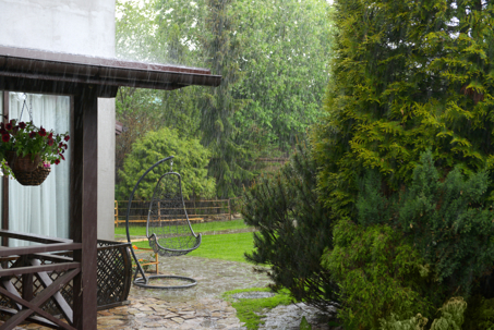 heavy rain falls on a stone patio and lush garden