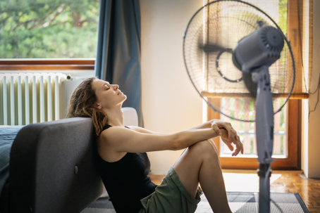 woman sitting in front of an electric fan